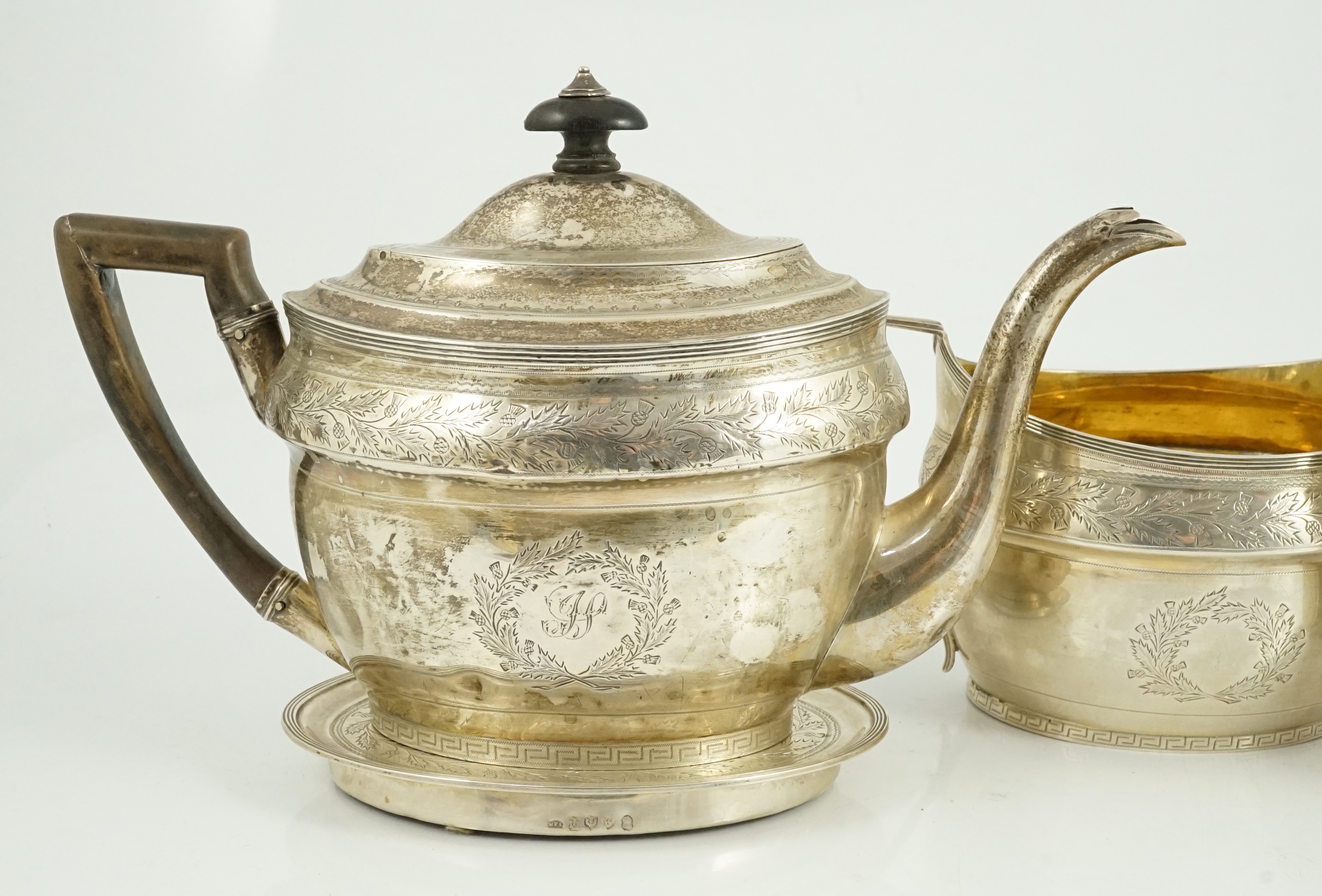 A George III Scottish chased silver oval three piece tea set and teapot stand, by William & Patrick Cunningham